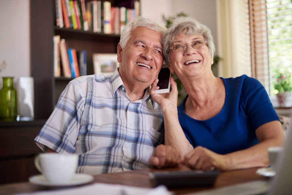 Grandparents talking on the phone at the table - Communication apps for seniors I StrongLink Technology