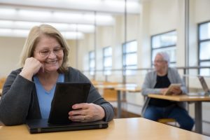 woman sitting on table holding digital tablet
