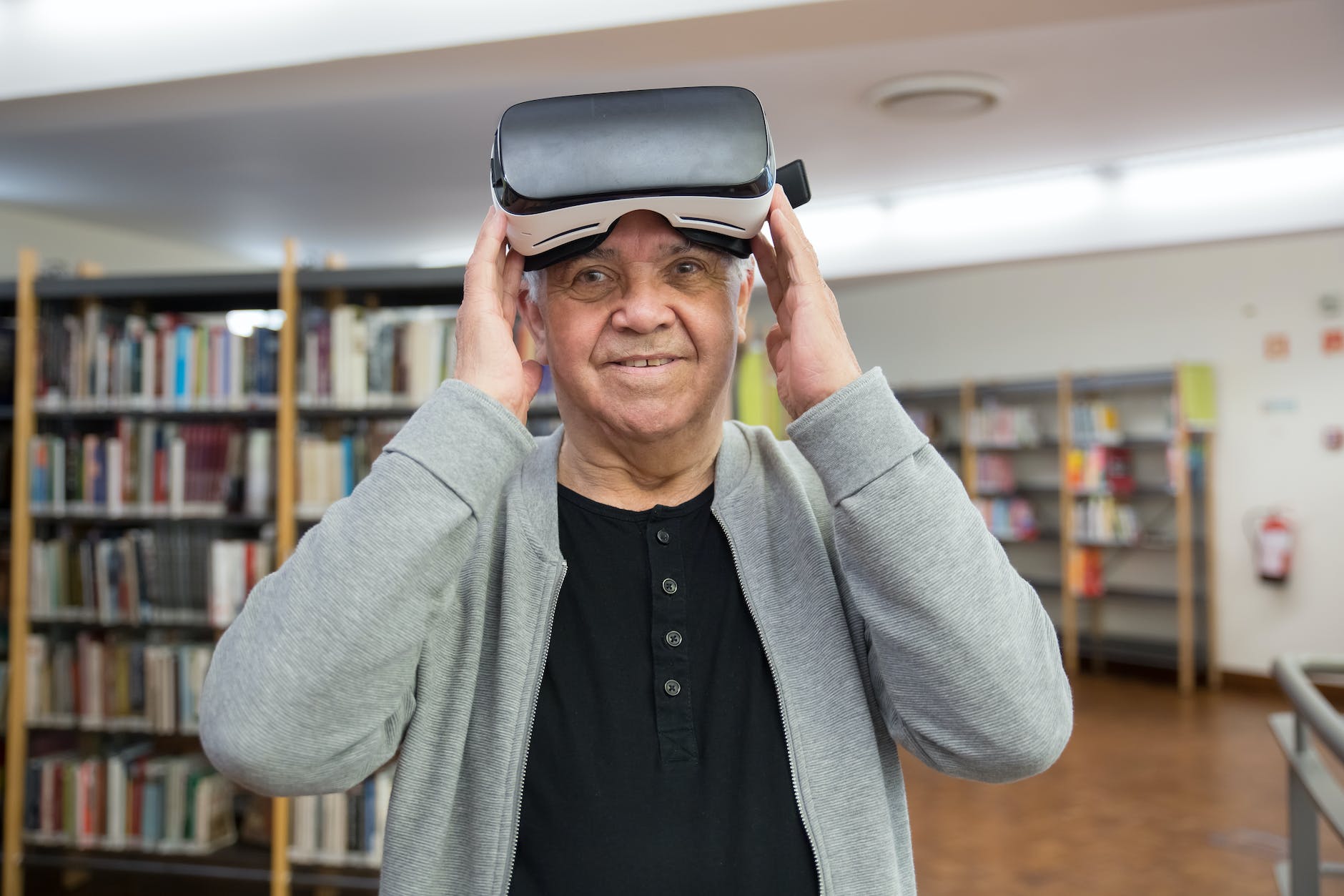 man in gray cardigan wearing virtual reality goggles Virtual Reality vs Augmented Reality I Sharanda Strong Henry I StrongLink Technology