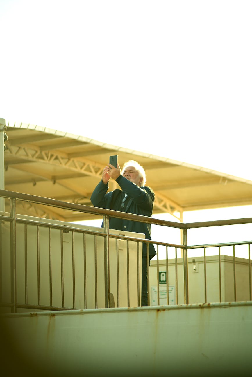 elderly man taking photo with smartphone on rooftop I StrongLink Technology I Sharanda Strong Henry