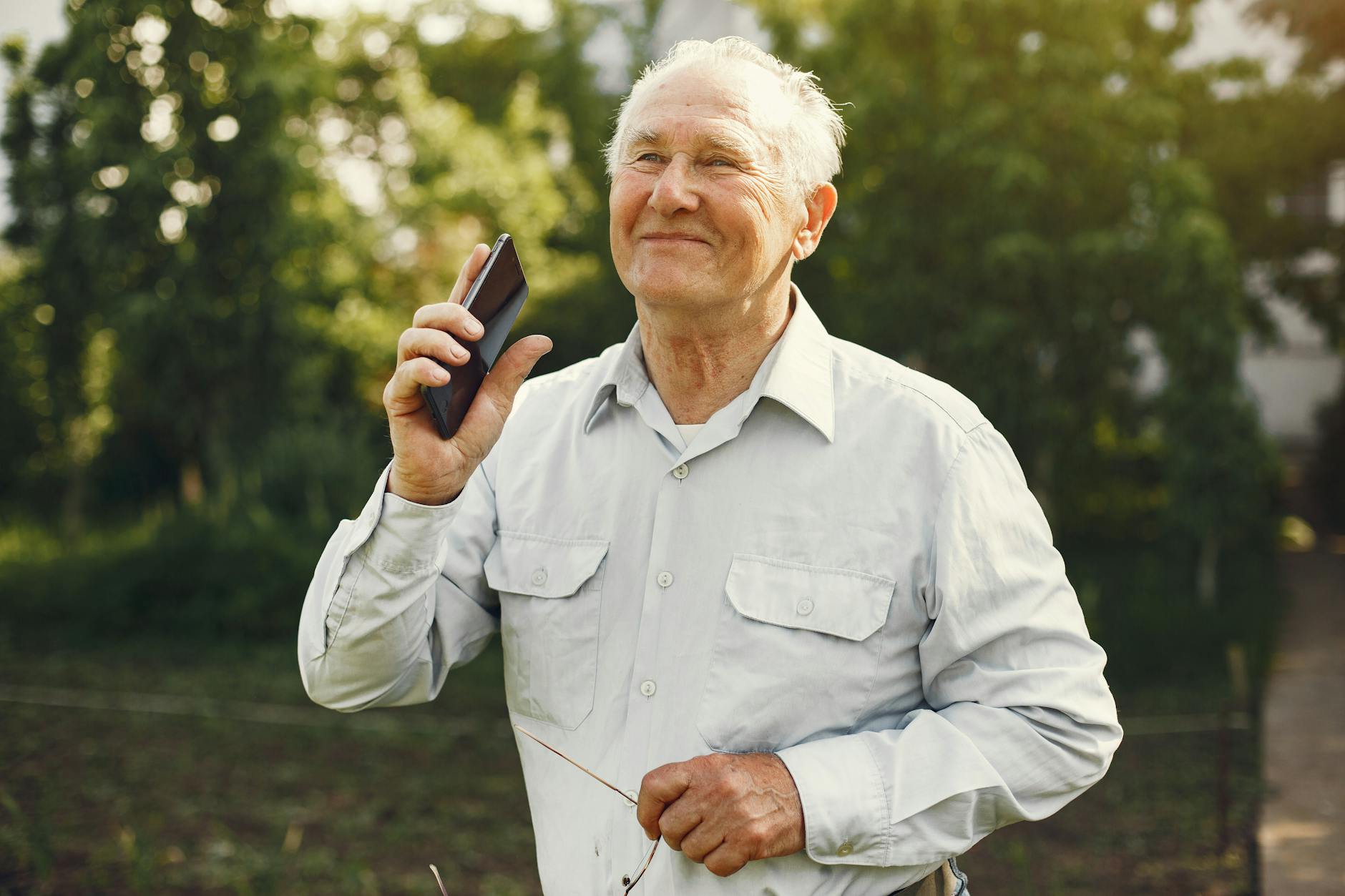 smiling elderly man holding a cellphone