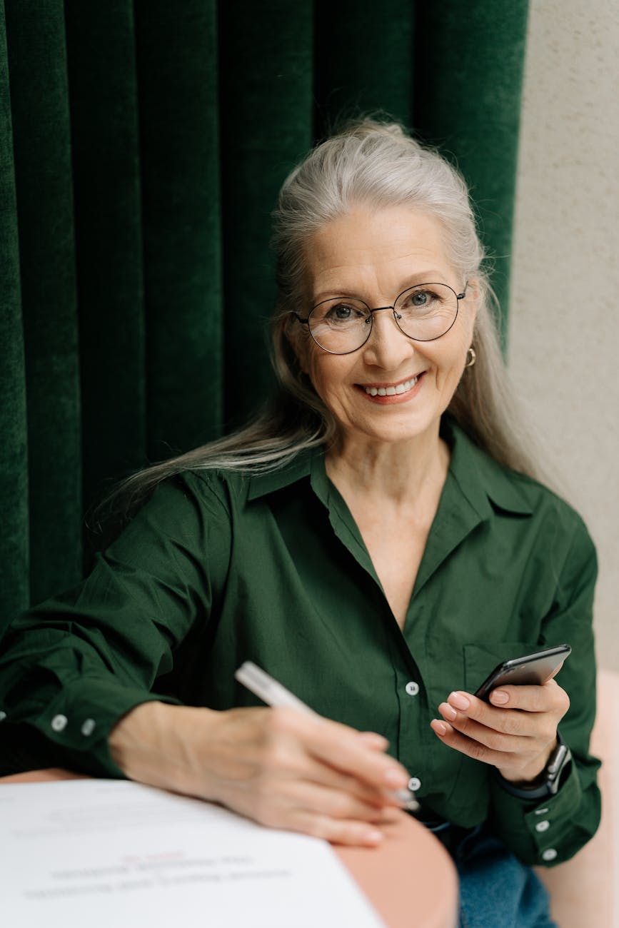 woman in green long sleeve shirt holding smartphone