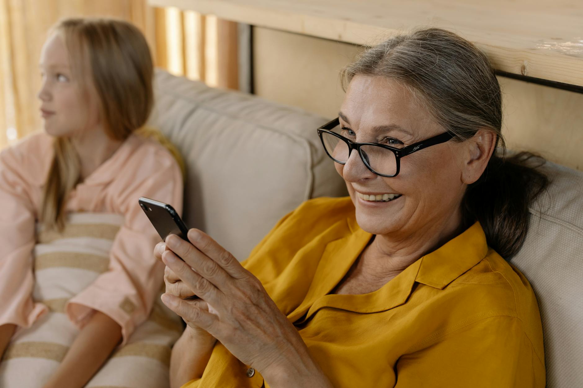 close up shot of an elderly woman wearing eyeglasses while holding a smartphone