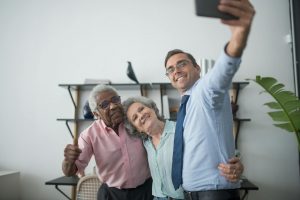 man holding a cellphone taking group selfie